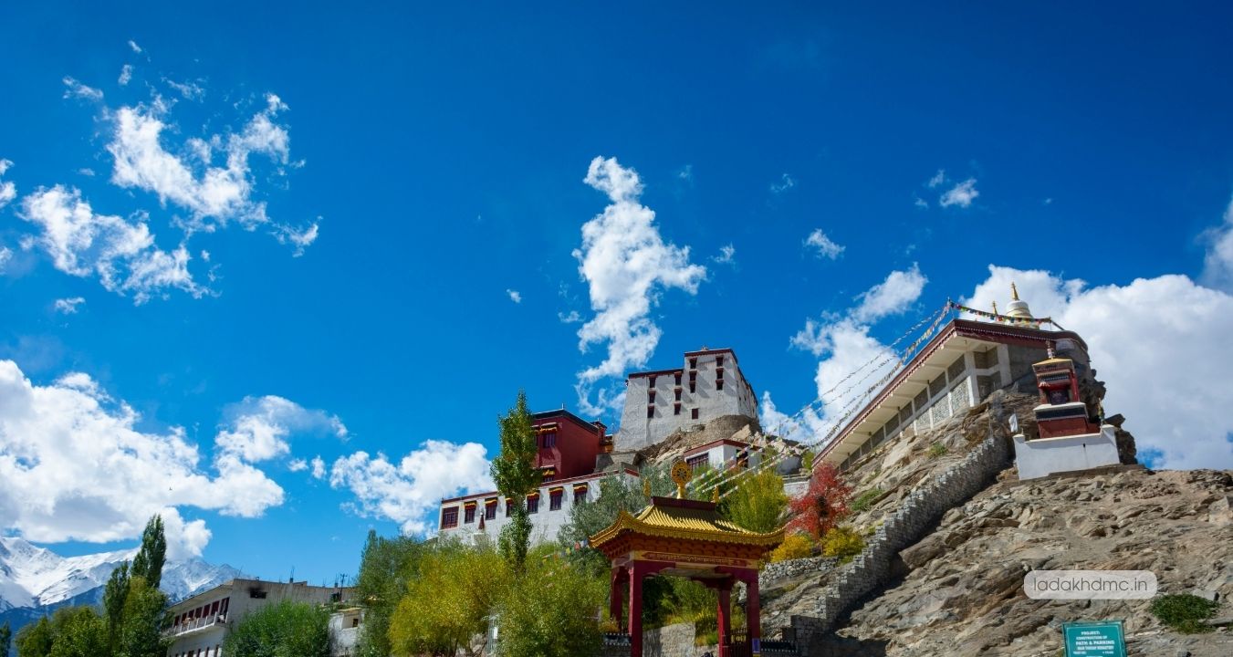 Interior of Hanle Monastery prayer hall with monks and colorful Buddhist murals in Ladakh