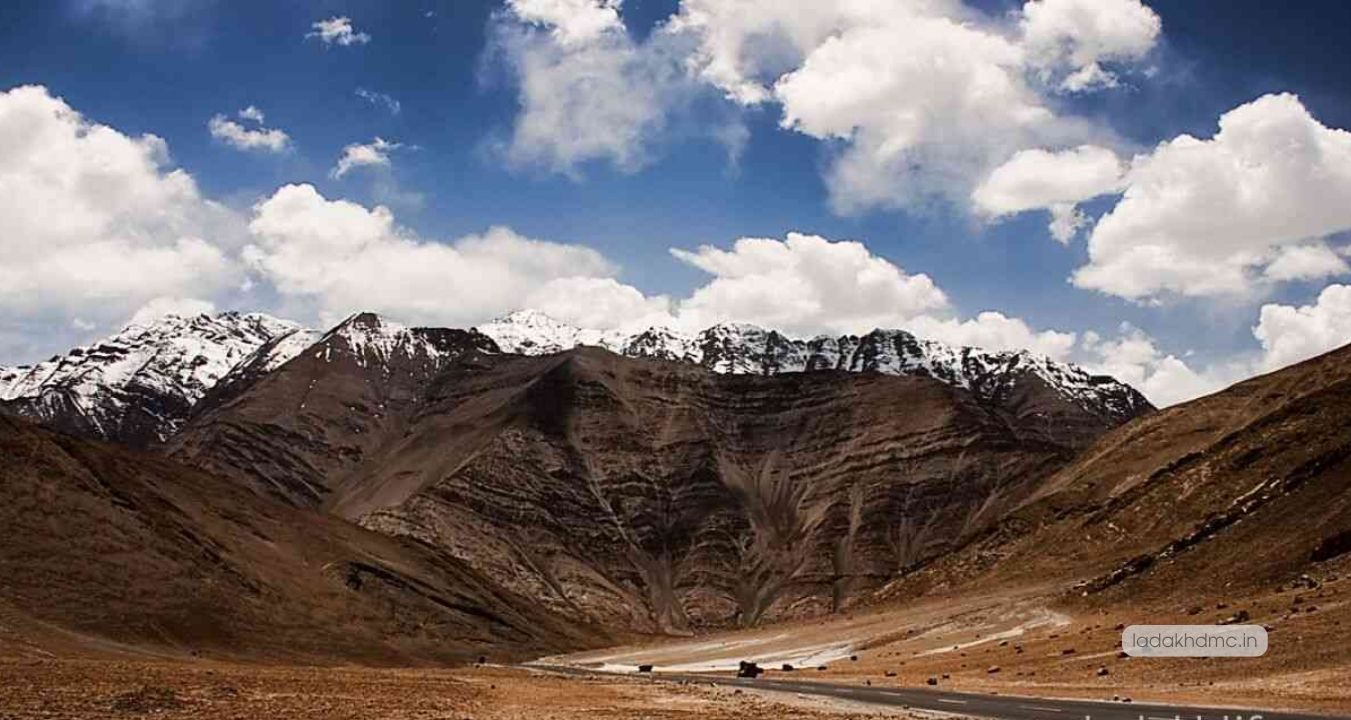 Panoramic view of Magnetic Hill showing road, vehicles, and surrounding mountains